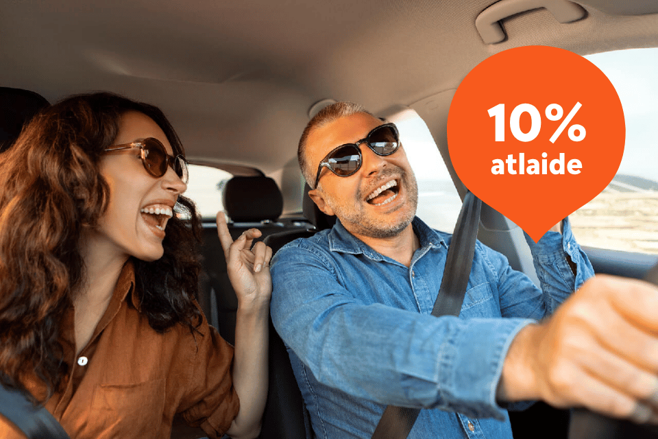 Smaidošs pāris izbauda jautru braucienu ar auto.