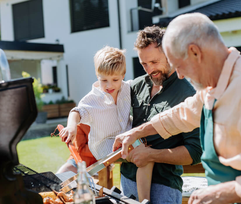 Grandfather with his son and grandson cooks food on the grill